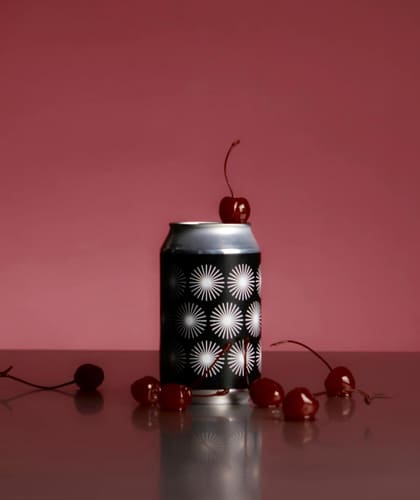 A spotted can with cherries on a red table